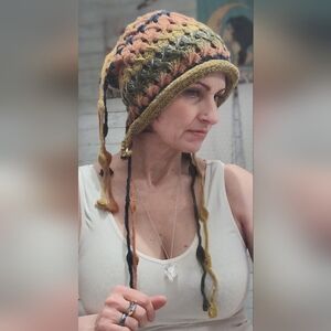 hand-crocheted multicolor beanie with ear flaps and tassel details.